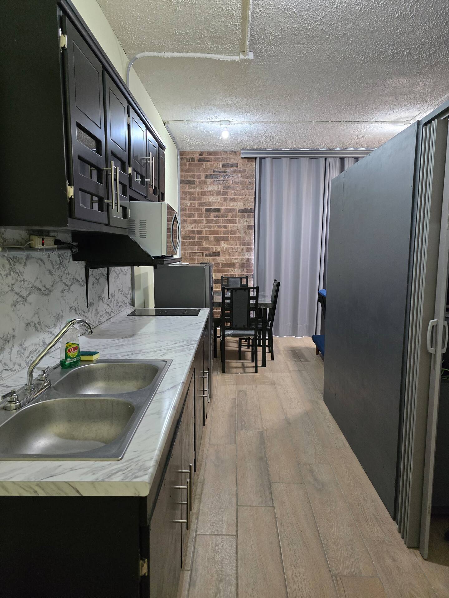 Cocina con alacenas oscuras, refrigerador y barra