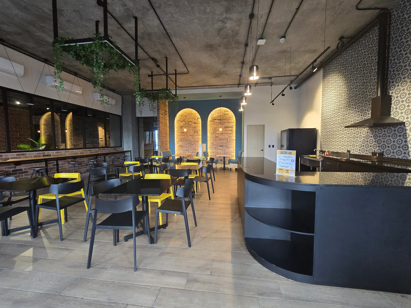 Zona de cowork con mesas, sillas amarillas y muros de ladrillo