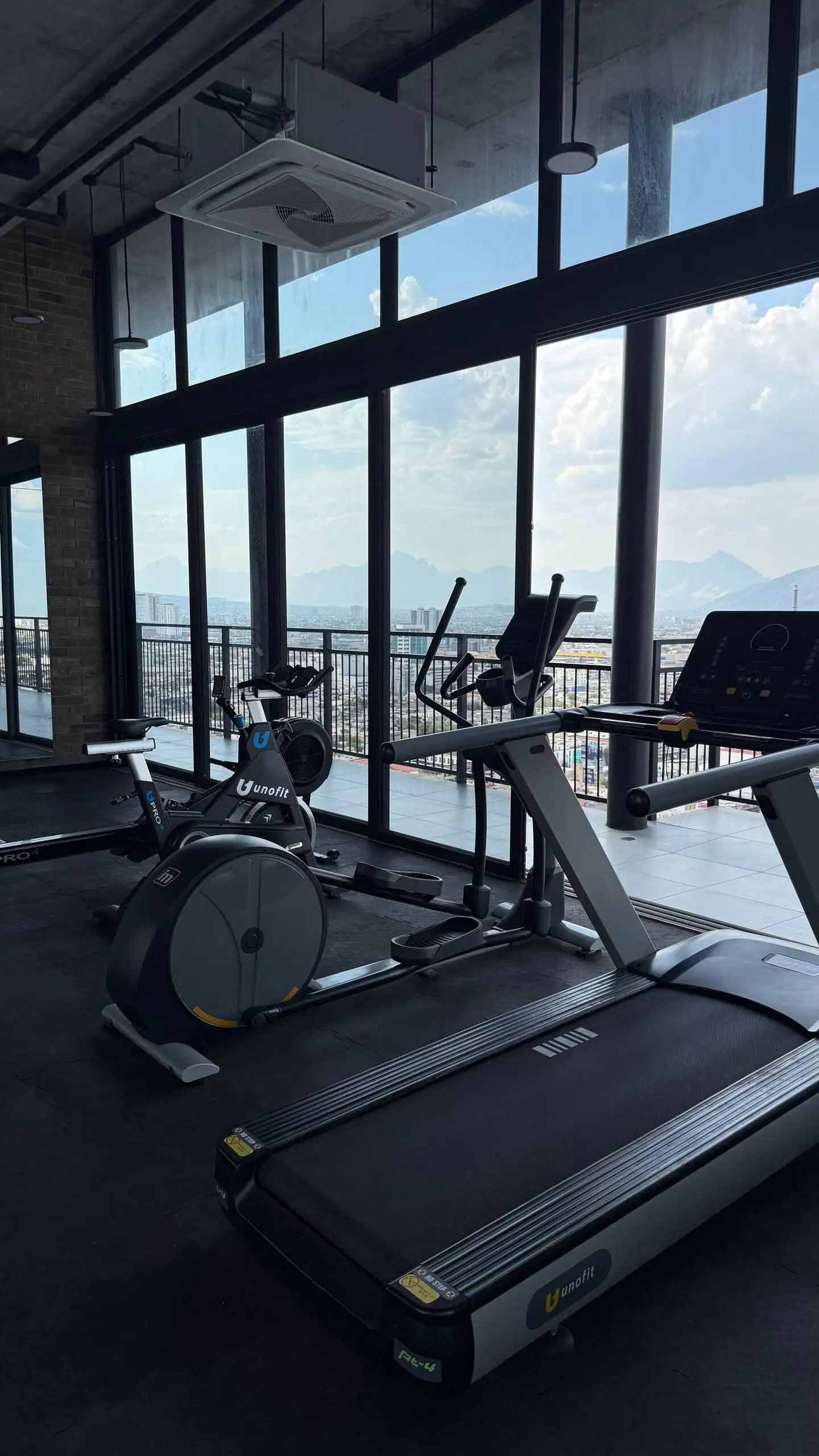 Gimnasio equipado con caminadora y bicicleta fija frente a los ventanales