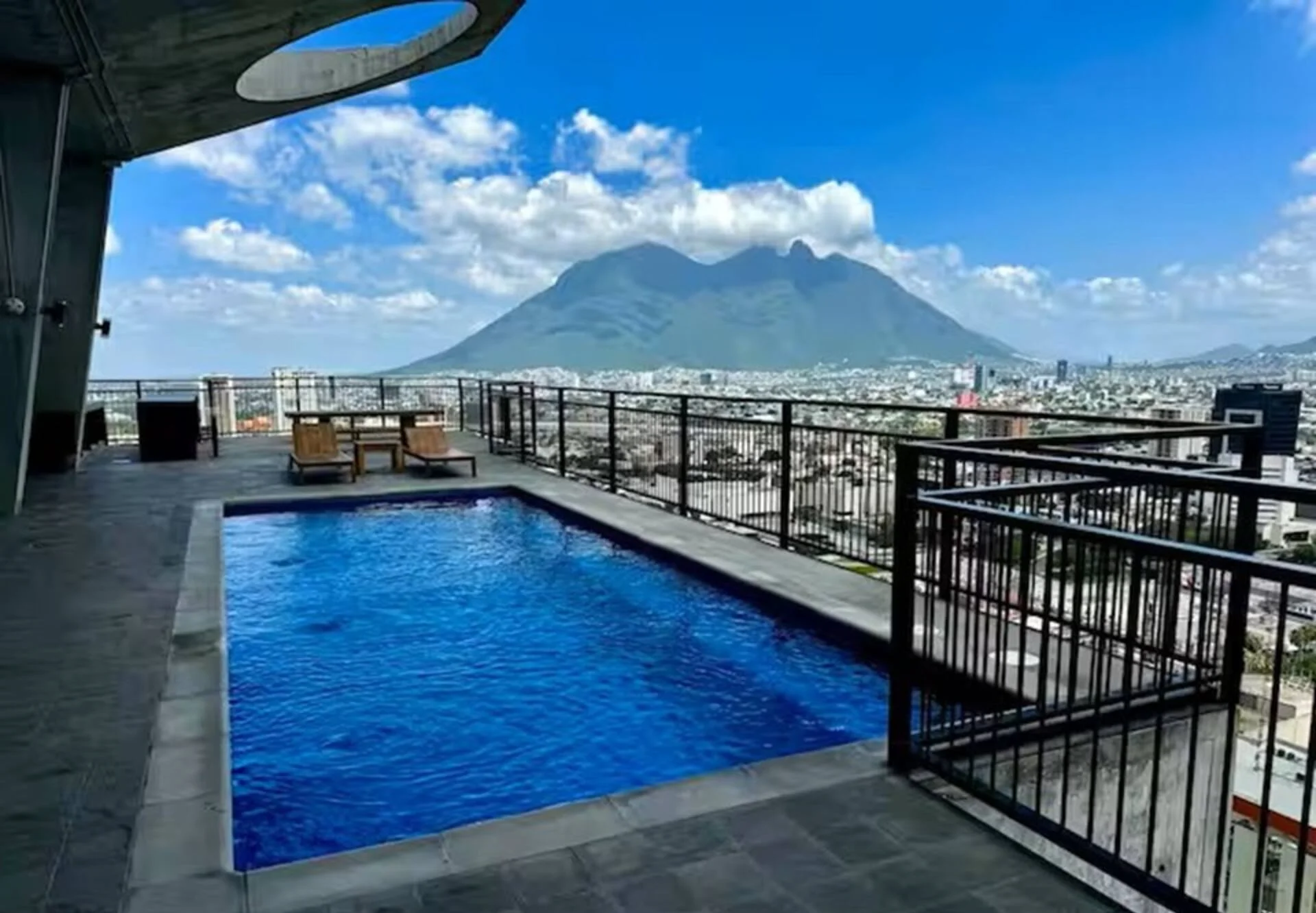 Alberca en la azotea de la torre con el Cerro de la Silla y la ciudad de Monterrey al fondo