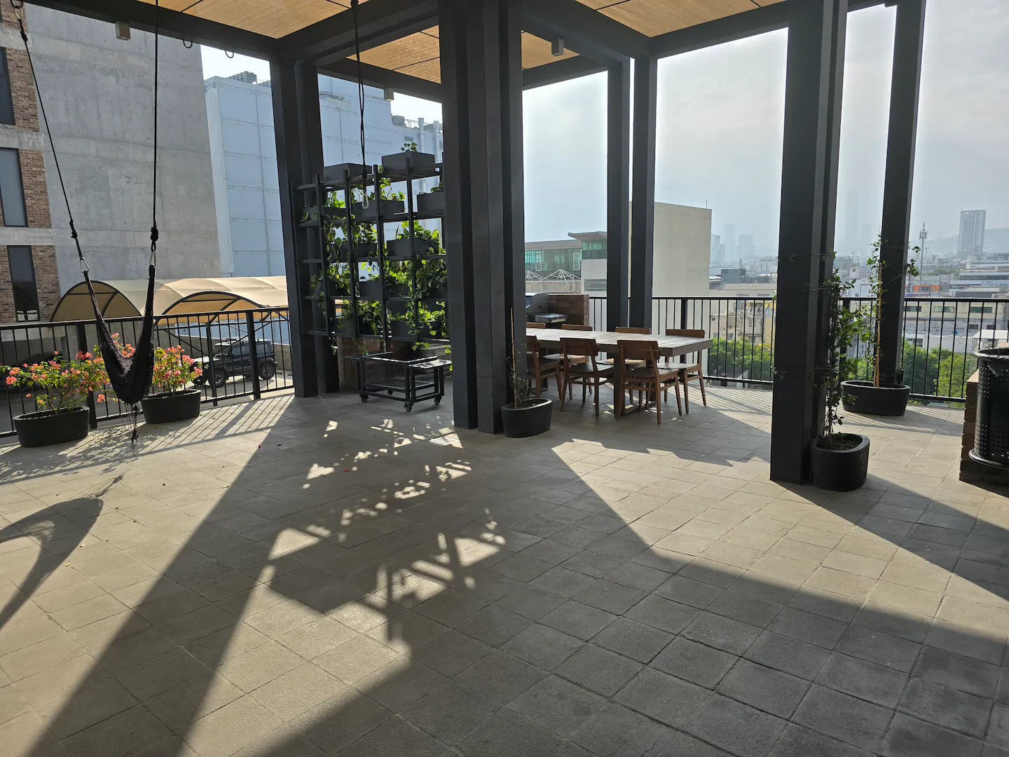 Terraza cubierta con mesas y hamacas, y la ciudad al fondo